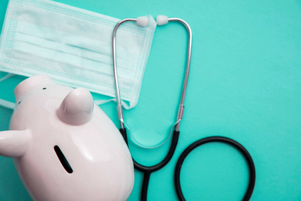 Cost of healthcare. Piggy bank money box with a medical doctors stethoscope - Photo, image