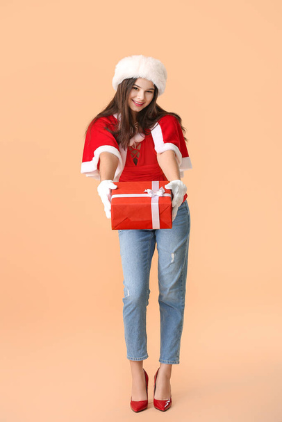 Όμορφη νεαρή γυναίκα ντυμένη σαν Άγιος Βασίλης με δώρο στο φόντο χρώμα - Φωτογραφία, εικόνα
