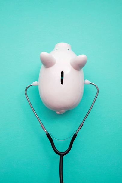 Cost of healthcare. Piggy bank money box with a medical doctors stethoscope - 写真・画像
