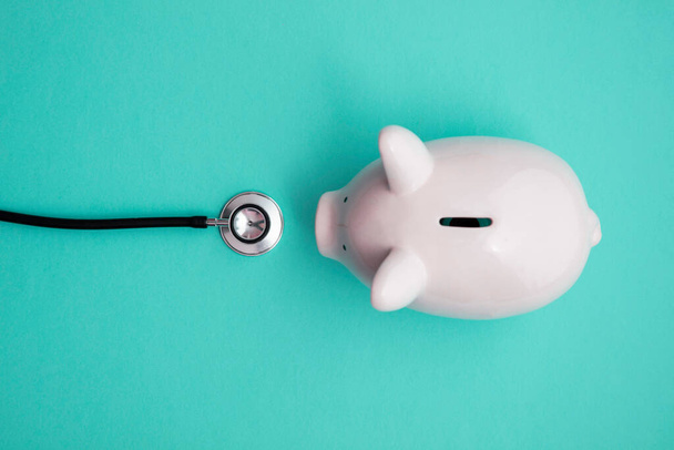 Cost of healthcare. Piggy bank money box with a medical doctors stethoscope - Fotó, kép