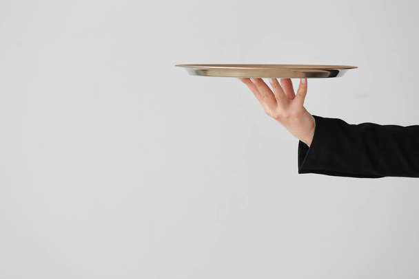 Kellnerhand mit leerem Tablett auf grauem Hintergrund - Foto, Bild