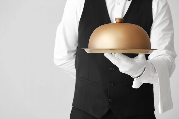 Male waiter with tray and cloche on grey background - Photo, Image