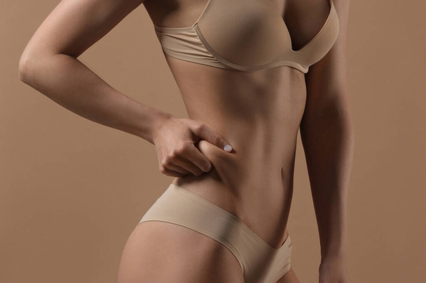 Thin woman shows fold of fat. Fitness, weight loss and body care - Valokuva, kuva