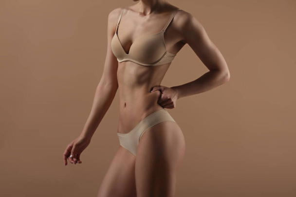 Thin woman shows fold of fat. Fitness, weight loss and body care - Photo, image