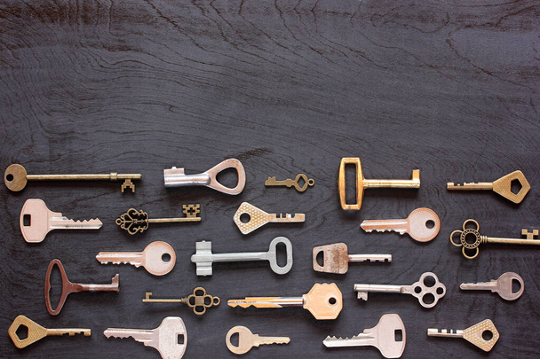various metal keys on a black wooden surface, background, top view. flat lay. - Foto, immagini