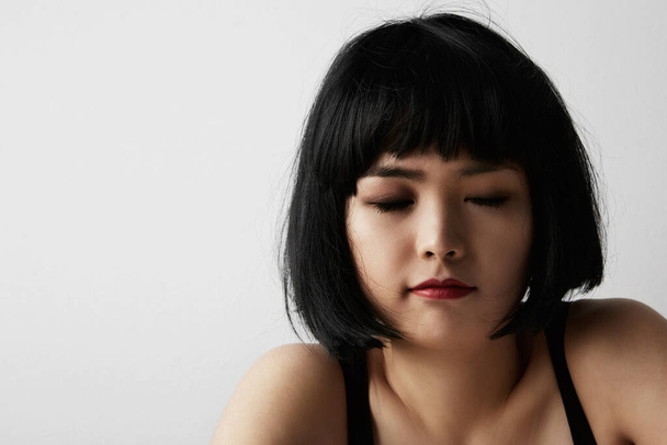Asian young girl with closed eyes over white studio background. Free space for text. - Foto, imagen