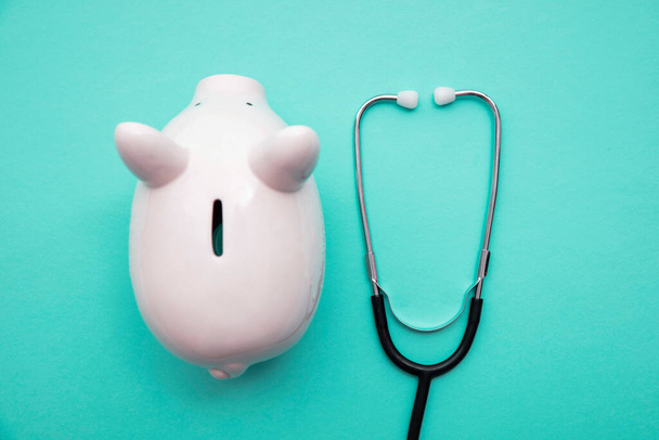 Cost of healthcare. Piggy bank money box with a medical doctors stethoscope - Valokuva, kuva