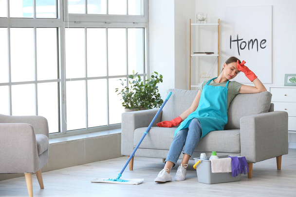 Tired young woman after mopping floor in room - Foto, afbeelding