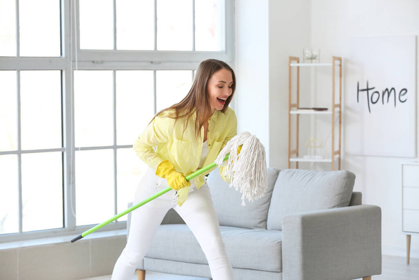Young woman having fun while mopping floor in room - Photo, Image