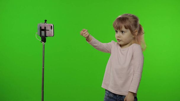 Tyttö lapsi tekee selfie vlog, bloggaaminen, videopuhelu matkapuhelimeen käyttäen monopodia
 - Valokuva, kuva