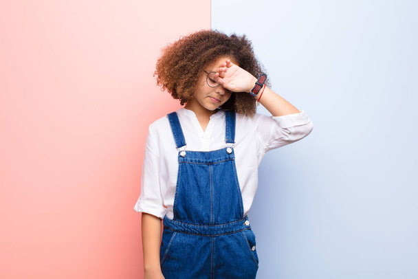african american little girl looking stressed, tired and frustrated, drying sweat off forehead, feeling hopeless and exhausted against flat wall - 写真・画像