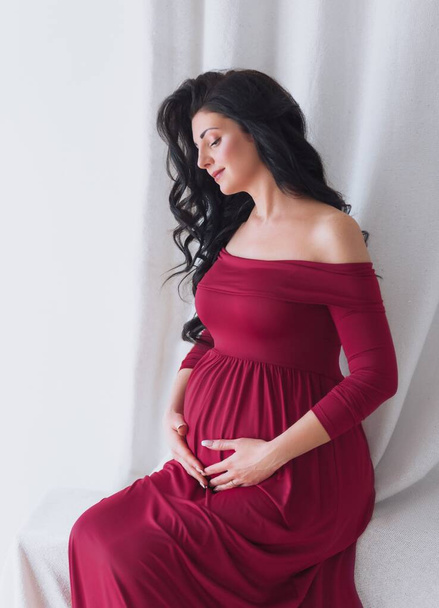 Красива вагітна жінка позує в студії
 - Фото, зображення