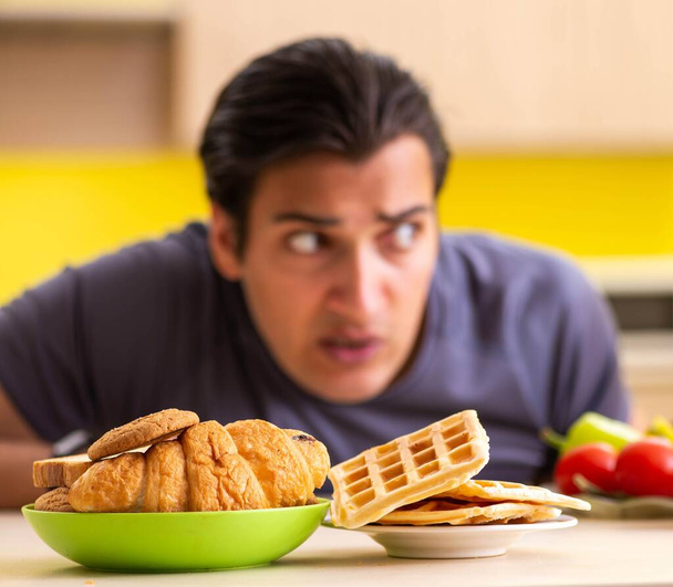 Hombre que tiene difícil elección entre la comida sana y no saludable
 - Foto, Imagen
