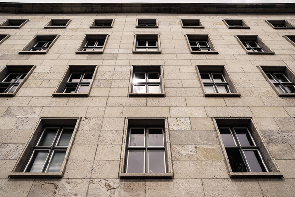 vista de ángulo bajo de un edificio gris con ventanas rectangulares en un día nublado
 - Foto, imagen