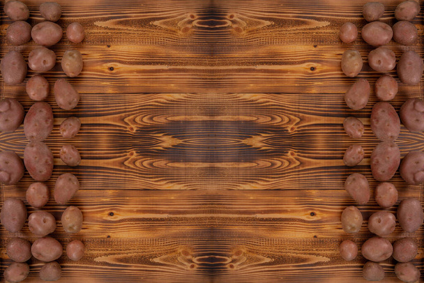 Φρέσκες κόκκινες πατάτες στο ξύλινο φόντο. Διπλή εικόνα, στη μέση με χώρο αντιγραφής, πάνω όψη - Φωτογραφία, εικόνα