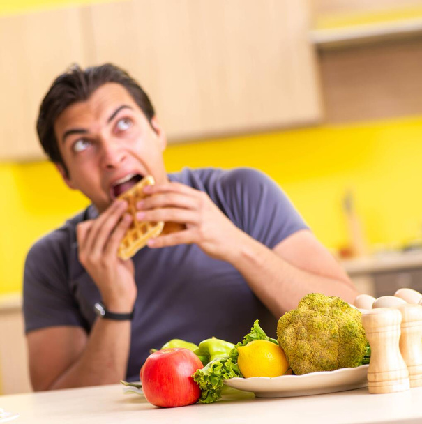 Uomo che ha una scelta difficile tra cibo sano e malsano - Foto, immagini