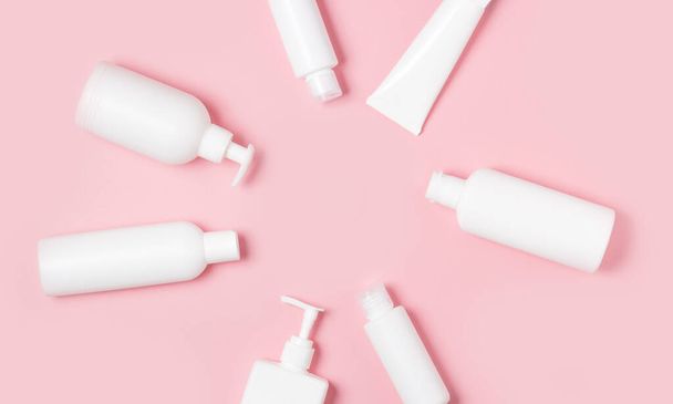 White plastic cans on a pink background. Cosmetics for skin care. Means for washing, disinfecting and washing. - Photo, Image