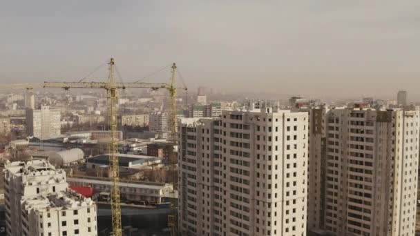 Budowa nowych nowoczesnych wieżowców biurowych i mieszkaniowych, suwnic wieżowcowych w kolorze żółtym. Panorama miasta przemysłowego. Budowa nowych budynków przez pracowników. - Materiał filmowy, wideo