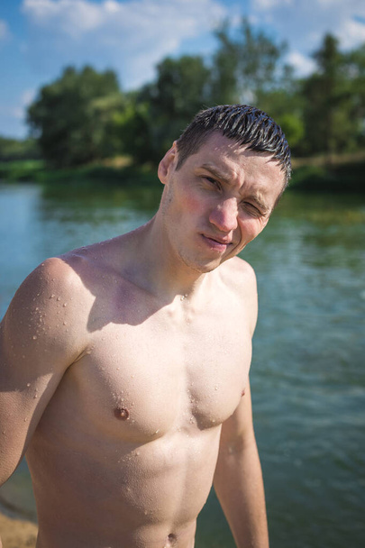 Portrait of a young guy by the river in the summer. - Valokuva, kuva