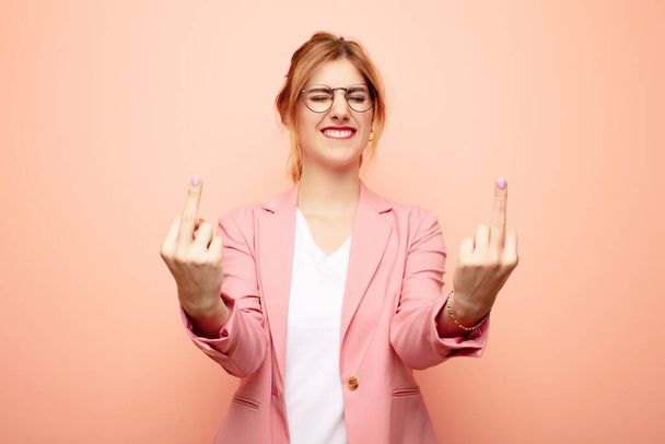 young pretty blonde woman feeling provocative, aggressive and obscene, flipping the middle finger, with a rebellious attitude. business concept - Fotoğraf, Görsel