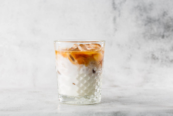 Glass with cold brew coffee and milk isolated on bright marble background. Overhead view, copy space. Advertising for cafe menu. Coffee shop menu. Horizontal photo. - Фото, изображение