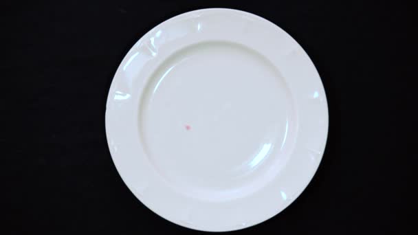 Mano masculina limpia migas de color brillante con un plato blanco sobre un fondo negro 4k. Primer plano tiro de migas
 - Metraje, vídeo