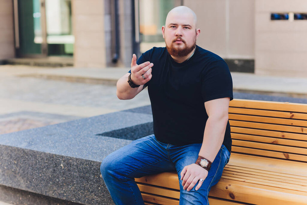 portrait of a bald handsome bearded man in a black t-shirt on the street, who looks away. - Fotografie, Obrázek