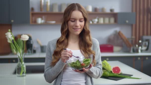 Beautiful girl eating fresh salad at home kitchen. Woman enjoying fresh food - Imágenes, Vídeo