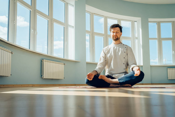 Человек практикует йогу. Молодой привлекательный мужчина делает дыхательные упражнения. Парень медитирует дома во время пандемии. Концепция релаксации и отдыха для изоляции. Слайд-шот
. - Фото, изображение