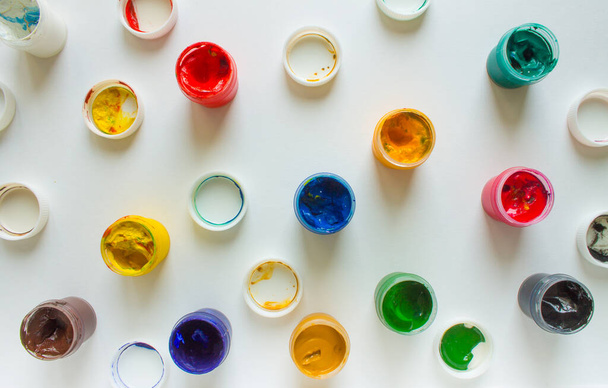 Multi-colored paints-plastic jars of gouache on a white paper background top view - Foto, imagen