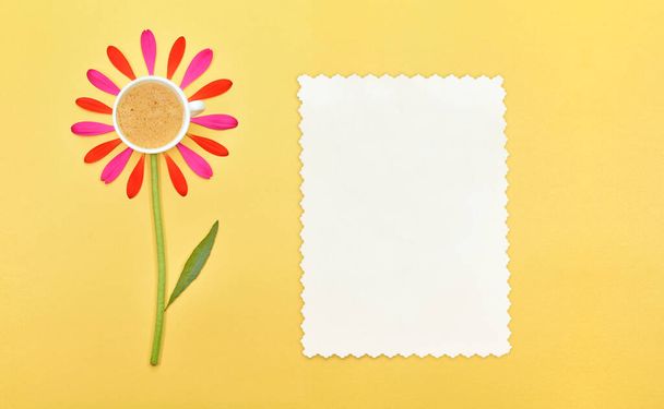 Good morning. A cup of coffee,  and a card with copy space for text, on a yellow background. A cup of coffee with flower petals on a yellow background. Spring or summer background with copy space for text: blank stationary template. Top view. Flat la - Photo, Image