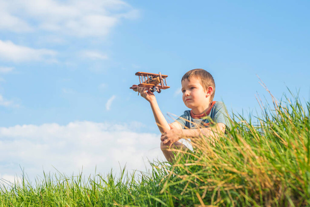 Petit garçon joue avec un jouet avion en bois. Enfant tient un jouet avion en bois. - Photo, image
