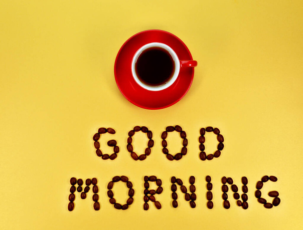 Egy csésze kávét, jó reggelt felirattal. Egy csésze kávé, elszigetelt háttérrel. Jó reggelt, kávébabból készült felirat.. - Fotó, kép