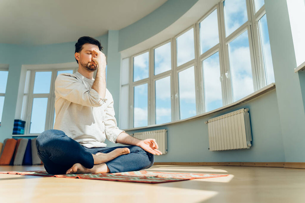 Man practice yoga. Young attractive male doing breathing exercises. Guy meditating at home along during the pandemic. Relaxation and resting concept for isolation. Slide shot. - Fotoğraf, Görsel