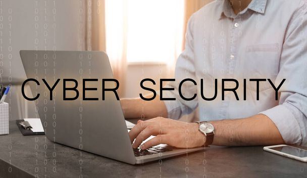 Cyber security concept. Man working with laptop at table indoors, closeup - 写真・画像