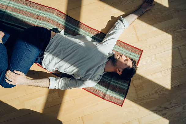 Man practice yoga. Young attractive male doing breathing exercises. Guy meditating at home along during the pandemic. Relaxation and resting concept for isolation. Slide shot. - Foto, imagen