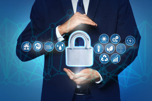 Home security concept. Man holding lock on light blue background, closeup - Fotó, kép
