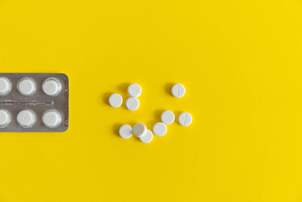 Top view on the pills in the package. White pills on yellow background. Medicine, medication, painkillers, tablet, medicaments, drugs, antibiotic, vitamin, treatment, capsule, dose. Pharmacy theme. - Foto, afbeelding