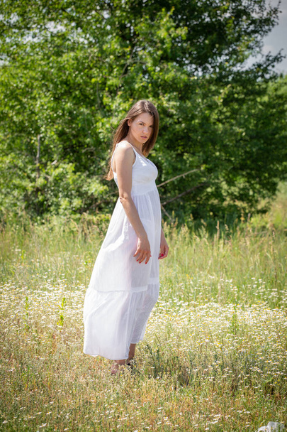Nuori nainen valkoisessa mekossa kävelee kesällä metsäpolulla
 - Valokuva, kuva
