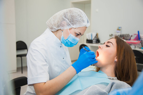 Young female dentist curing patients teeth filling cavity - Foto, afbeelding