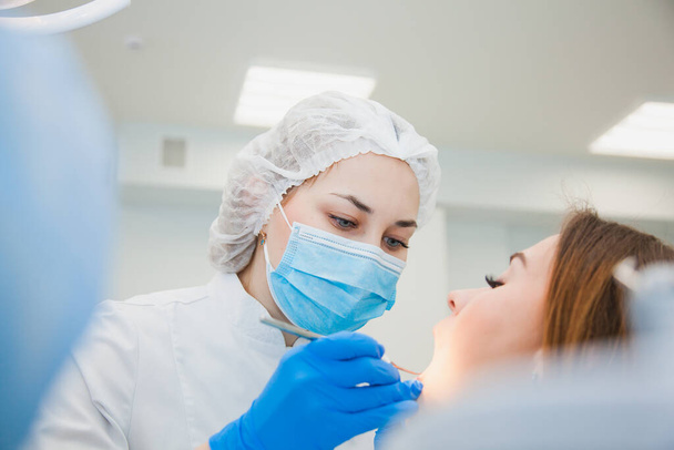 Молодая женщина-стоматолог лечит зубы пациентов, заполняя полость
 - Фото, изображение