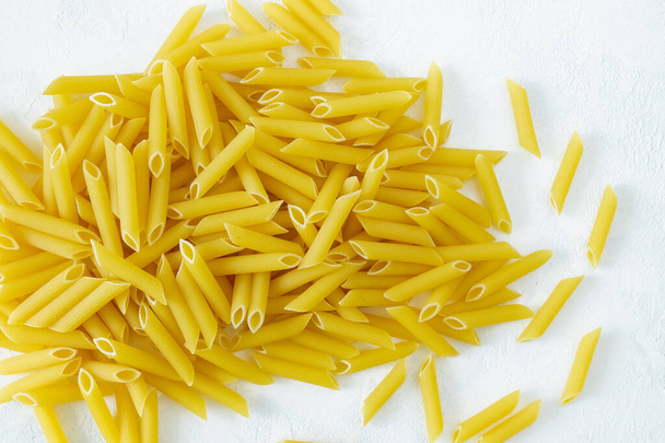 A close-up of penne paste on a light background. Italian cuisine, healthy eating concept. Horizontal orientation, selective focus, view from above. - Foto, immagini