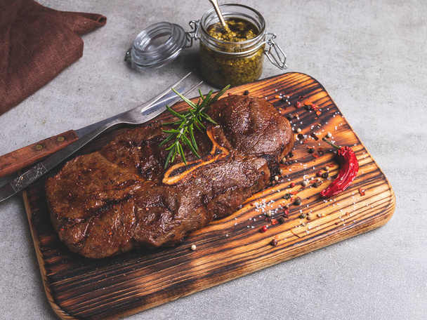 grilled beef steak with bone on a cutting board spices - Zdjęcie, obraz