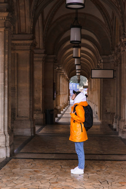 donna turista a piedi con zaino in impermeabile giallo città turismo copia spazio - Foto, immagini