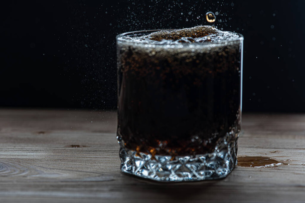 üveg egy ital sötét színű oldalnézetet, fröccsenések és hab az italból. Szelektív fókusz - Fotó, kép