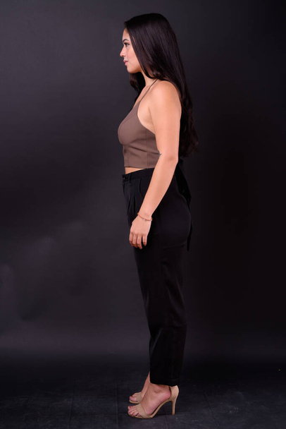 Studioaufnahme einer jungen schönen multiethnischen Geschäftsfrau vor schwarzem Hintergrund - Foto, Bild