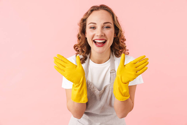 Picture of happy smiling woman housewife isolated over pink wall background in gloves. - Fotografie, Obrázek