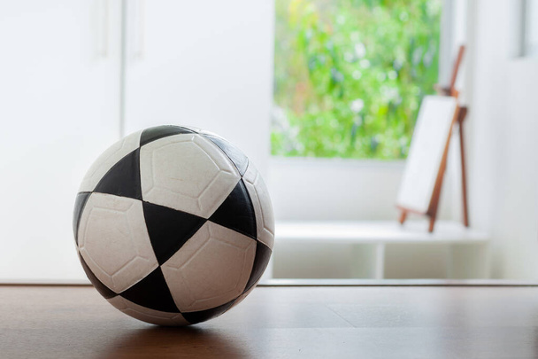 pelota de fútbol dentro de una habitación con una ventana inferior y un marco de madera
 - Foto, Imagen