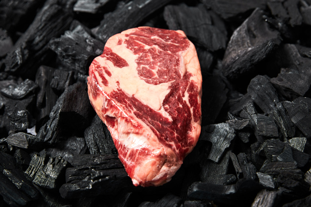 top view of fresh raw steak on black coals - Photo, Image