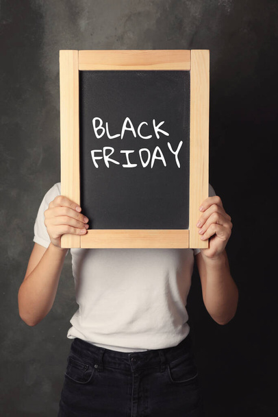 Woman holding blackboard with text BLACK FRIDAY on dark background - Foto, Imagen